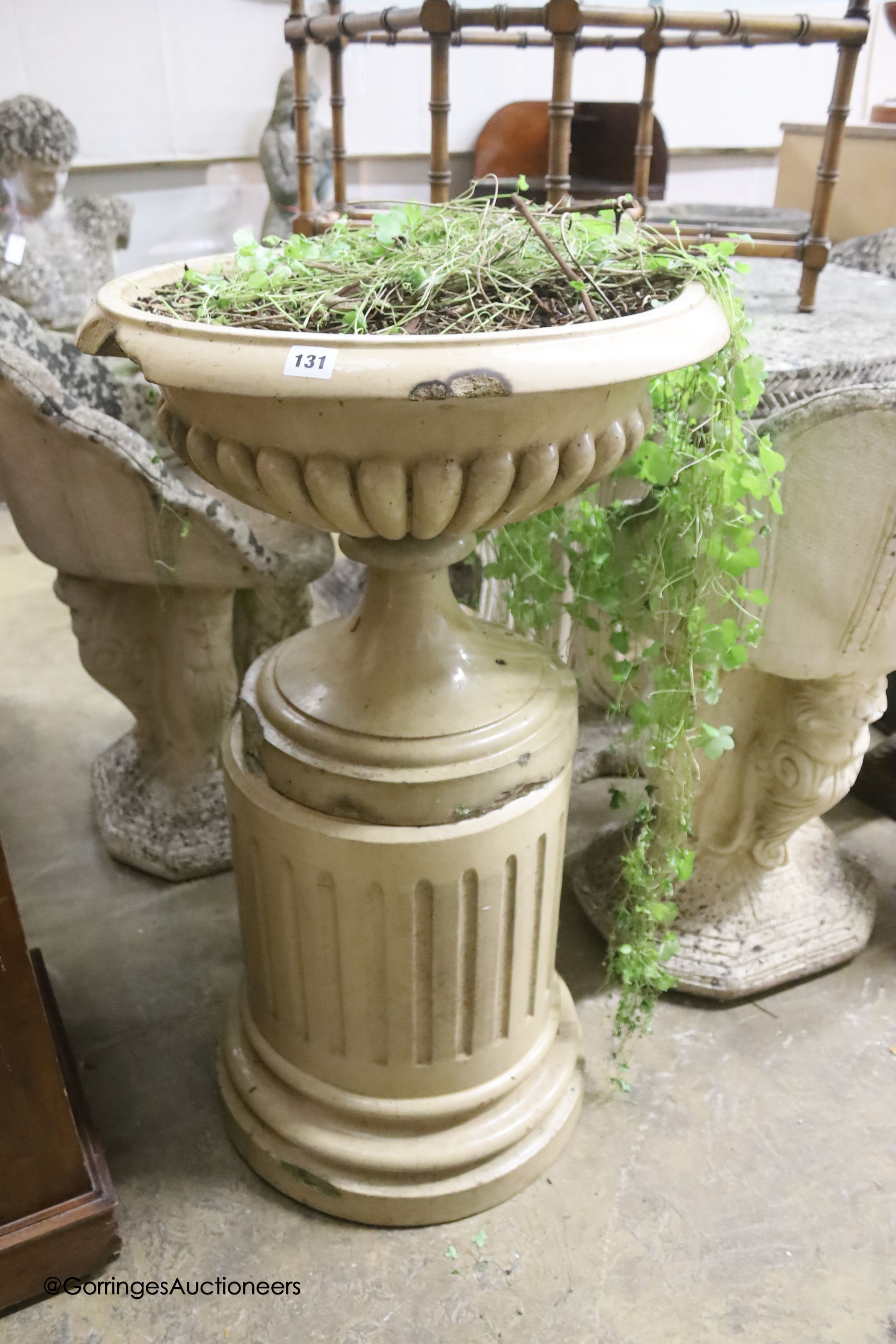 A buff-glazed stoneware garden urn on fluted pedestal